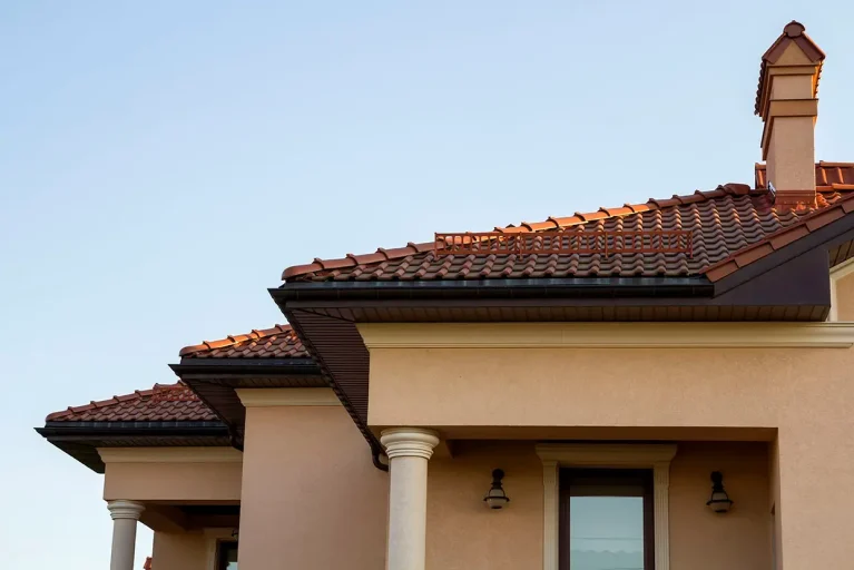 Close up of spacious brown shingle roof of modern luxurious expensive residential cottage house with three chimneys, big windows and gutters pipes. Construction, sale, buying and mortgage concept.
